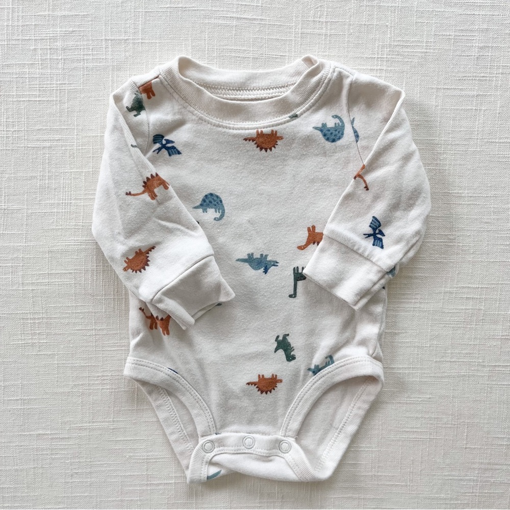 Carters baby boy long sleeve onesie in beige and orange dinosaur print.